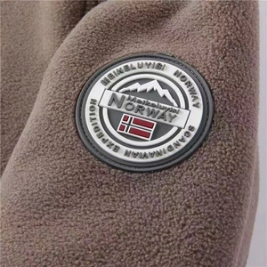 Detail of embroidered round patch on brown thick fleece jacket showing outdoor theme