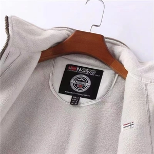 Detail of soft thick fleece lining and brand label on a beige outdoor warm jacket