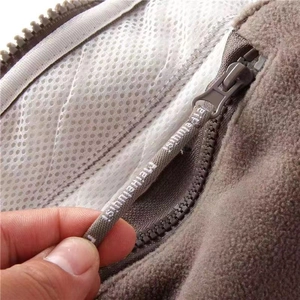 Detail of brown fleece jacket showing zipper with woven lanyard and white mesh lining
