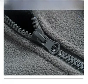 Detailaufnahme des Reißverschlusses und der strukturierten Fleece-Textur der grauen Jacke