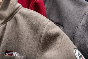 Detailed close-up of thick outdoor fleece jacket texture and embroidered Norway flag