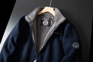 Detail of navy blue fleece jacket with embroidered Norway flag and brand logo on chest