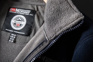 Detail of the navy fleece jacket collar featuring a Norway logo and zip closure