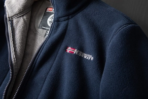 Detailed close-up of navy fleece jacket featuring Norwegian flag embroidery and zipper