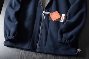 Detail of dark blue fleece jacket showing zipper, elastic cuffs and drawstring hem