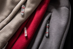 Detailed macro view of fleece outdoor jacket zippers with reflective puller tabs