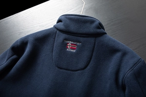 Detail view of navy blue fleece jacket with embroidered Norway flag and regional study text