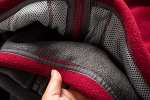 Detail view of red fleece jacket featuring thick grey lining and mesh interior fabric
