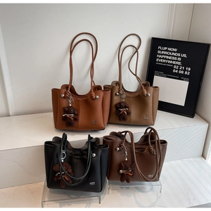 Dettaglio di eleganti borse tote in quattro colori con ciondoli a forma di orsetto