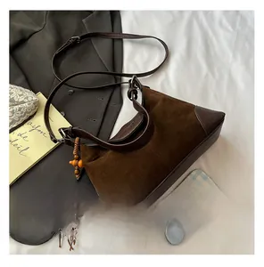 Detailed view of brown suede crossbody bag featuring a wooden bead tassel and leather accents