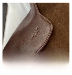 Macro shot of dark brown suede and smooth leather stitching with embossed logo
