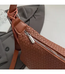 Detail of woven crescent shoulder bag with smooth silver zipper and adjustable strap