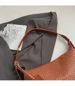 Close-up of brown woven texture on PU leather shoulder bag with slim strap and minimalist style