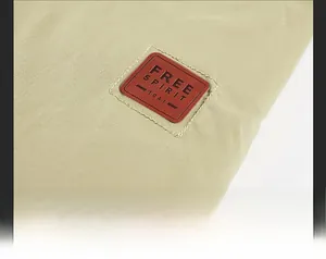 Dettaglio della toppa in pelle marrone cucita sul tessuto in twill kaki del parka invernale