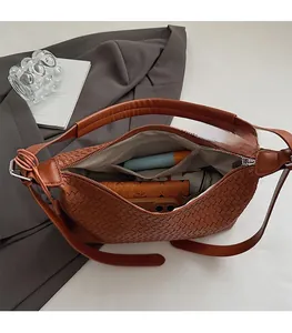 Detail of spacious interior with zipper pockets in a brown woven leather hobo bag