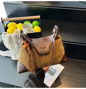 Detail of olive green suede tote bag with brown leather trim and decorative bead tassel