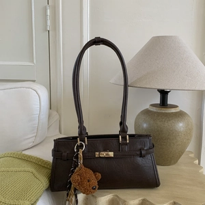 Detail of dark brown leather tote with gold buckle and cute bear plush charm