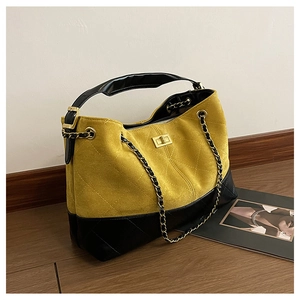 Close-up of yellow suede and black quilted leather bag with golden twist lock detail
