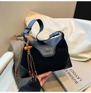 Detail of black suede and leather hobo bag with unique wood gourd tassel pendant