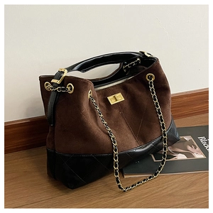 Detailed view of brown quilted suede texture and gold chain strap on a tote bag