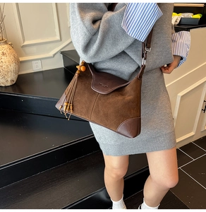 Detail of vintage brown suede shoulder bag with tassel and embossed logo texture