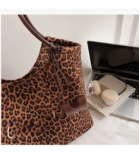 Detailaufnahme der Tragetasche mit Leopardenmuster, weißer Stickerei und Leder-Schultergurt