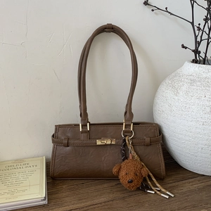 Detail of dark brown faux leather underarm bag with vintage texture and golden lock