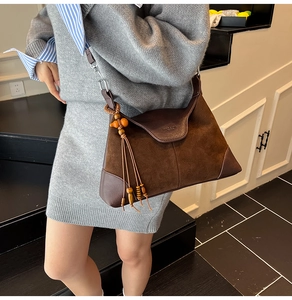 Detail of suede crossbody bag featuring retro wood bead tassel and adjustable strap