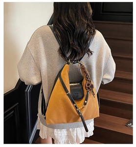 Detail of retro mustard suede tote bag with geometric pendant on model at stairs