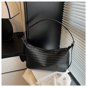 Close-up of black Intrecciato woven leather shoulder bag with zipper and round charm