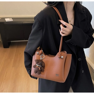 Borsa a secchiello in pelle marrone a grana con ciondolo a forma di orsetto e logo