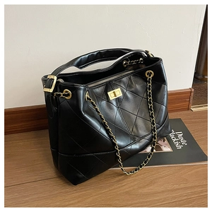 Detailed view of quilted black leather tote featuring gold chain and turn-lock closure