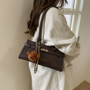 Detail view of deep brown vintage shoulder bag with metal twist lock and plush bear charm