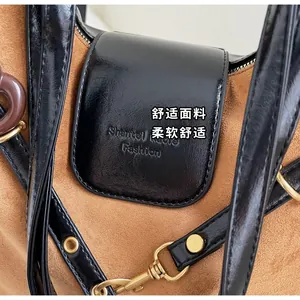 Detail of suede and leather contrast with golden hardware and brand logo embossing