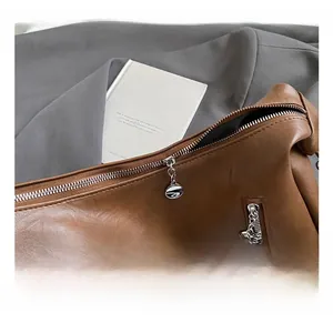 Close-up of premium silver metal zippers and vintage brown leather texture on a tote bag