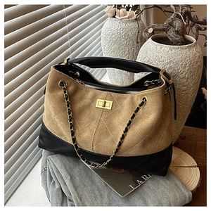 Detail of quilted brown suede tote bag with metal chain strap and golden twist lock clasp