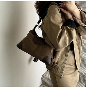Detailed view of olive green suede shoulder bag with brown leather trim and side drawstring