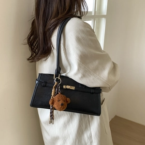 Detail of black faux leather shoulder bag with gold twist lock and cute bear charm