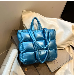 Detail of blue metallic quilted puffer tote bag with glossy texture and stitched squares