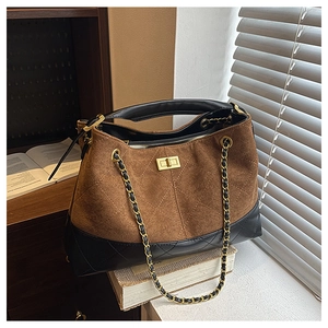Close-up of caramel suede tote with quilted black leather and golden turn-lock