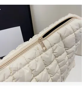 Detail of smooth gold zipper and beige quilted cloud bag fabric texture close-up