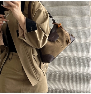 Detail of khaki suede crossbody bag with brown leather trim and wooden bead drawstring