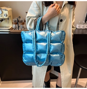 Close-up of shiny blue quilted down tote bag with metallic finish and padded handles
