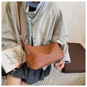 Detail of coffee brown woven tote bag featuring soft faux leather texture and round charm