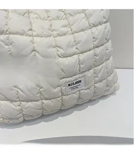 Detail shot of the white quilted tote bag featuring padded fabric and a logo patch