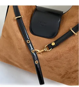 Close-up of brown suede bag with black leather strap and premium gold metal ring buckle