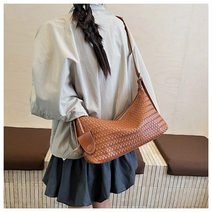 Detail view of the large brown woven leather hobo bag showing texture and crossbody strap