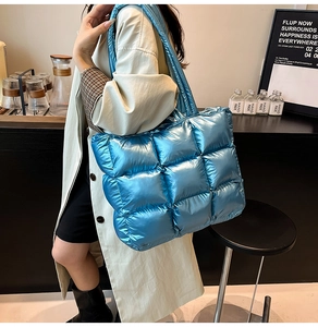 Quilted puffer tote bag in bright blue metallic finish shown on a model in a cafe