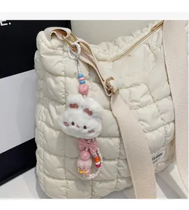 Detail of white plush rabbit charm with colorful beads hanging on a quilted bag side