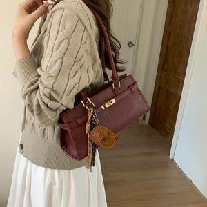Detail of burgundy leather shoulder bag with gold twist lock and cute bear charm